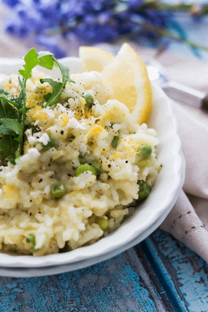 a bright lemony risotto served in a white bowl and topped with arugula