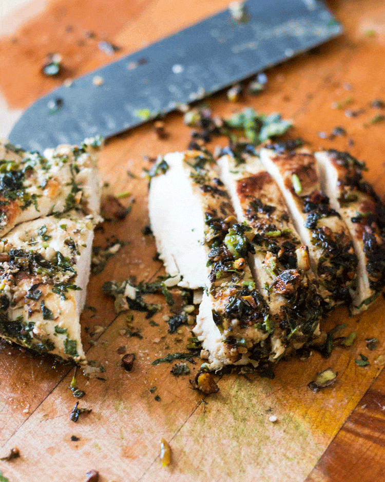Nut Crusted Chicken Breasts sliced on a wooden chopping board