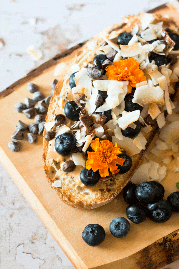 close up shot of almond butter coconut toast with chocolate drizzle loaded with blueberries 
