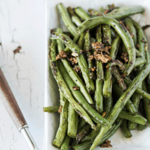 Garlic pepper skillet beans on a white dish topped with crispy garlic 