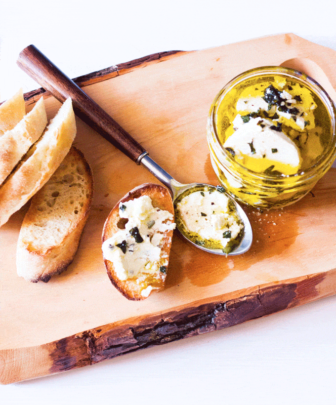 wooden board with fresh baguette and Marinated Goat Cheese Log with Fresh Garden Herbs