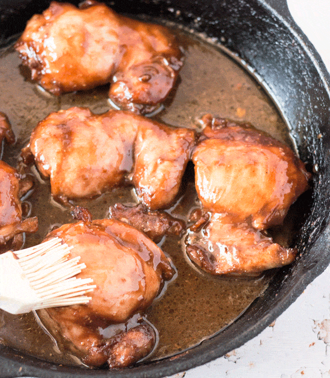 Basting the chicken thigh with a white silicone baster for One Skillet Honey Pomegranate Balsamic Glazed Chicken Thighs