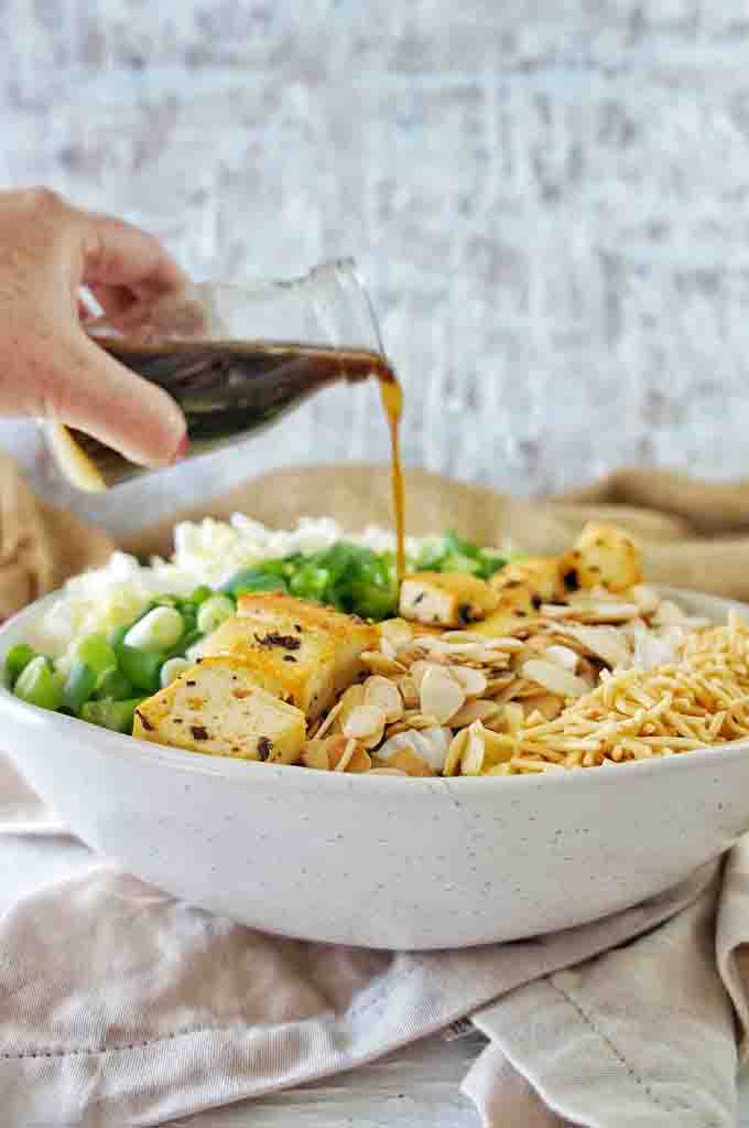 Pouring the dressing into Crispy Tofu Crunchy Noodle Salad