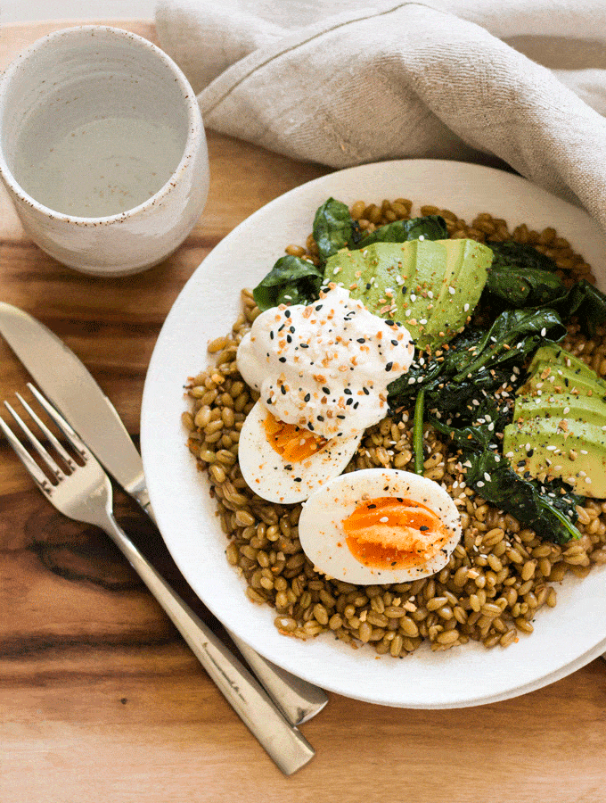 flat lay of Cumin Spiced Farro Breakfast Bowl Recipe (with instant pot instructions). Food is served on a white plate with a wooden background.