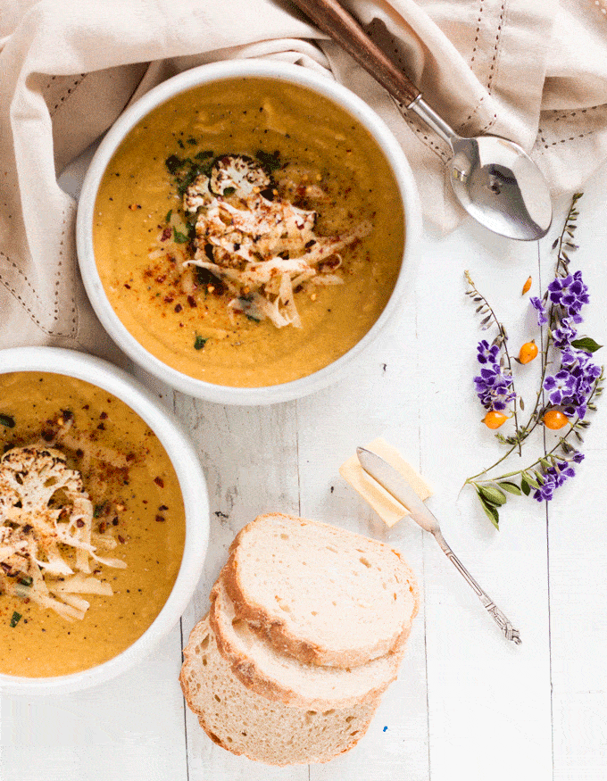 Cheesy Broccoli Cauliflower Soup served in white bowls with bread and butter