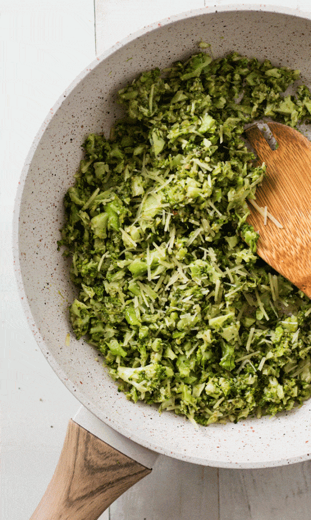 broccoli rice being sauteed in a small white saucepan