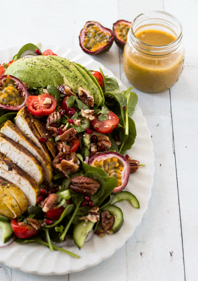 Salad served on a white platter with passionfruit dressing in a glass jar