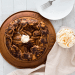 warm apple crostata on a wooden board surrounded by fresh cream, star anise and cinnamon