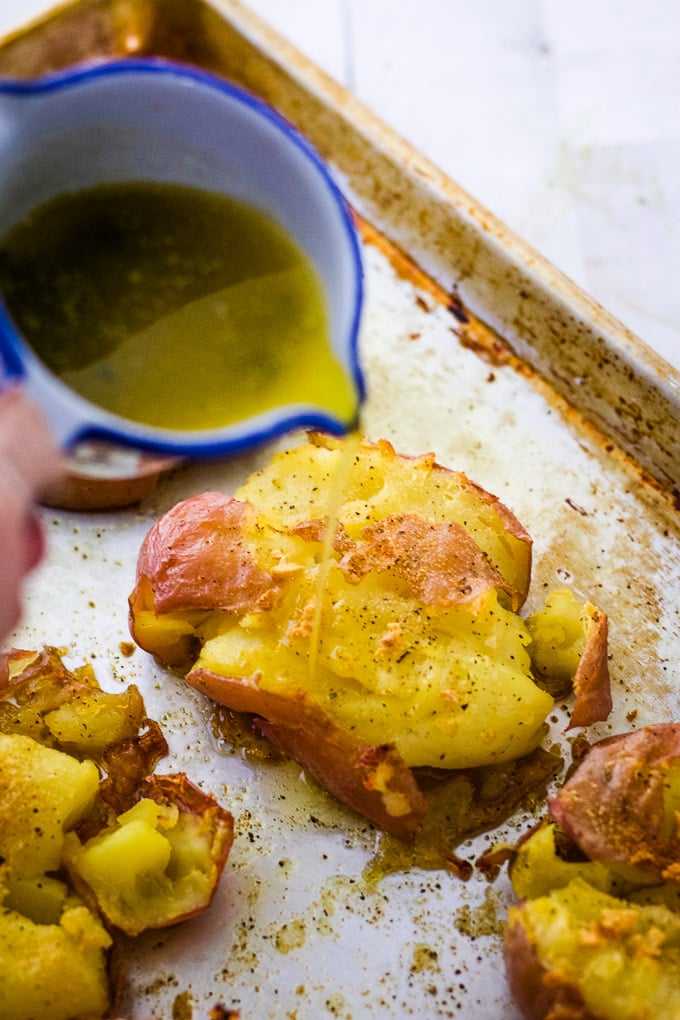 pouring melted butter on greek style potatoes