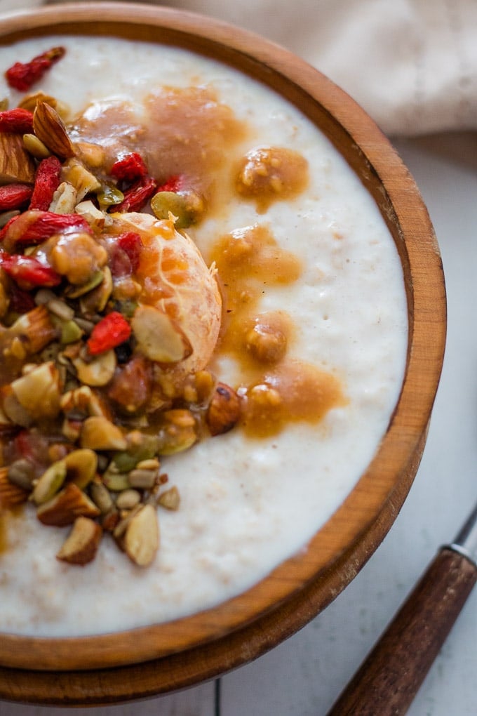 winter porridge in a wooden bowl topped with nuts and seeds