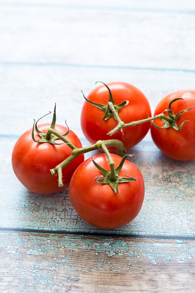 4 tomatoes on a blue background