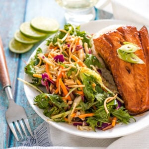 teriyaki salmon on a white plate with slaw