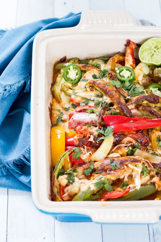 chicken fajita casserole in a blue le creuset casserole dish set against a white background