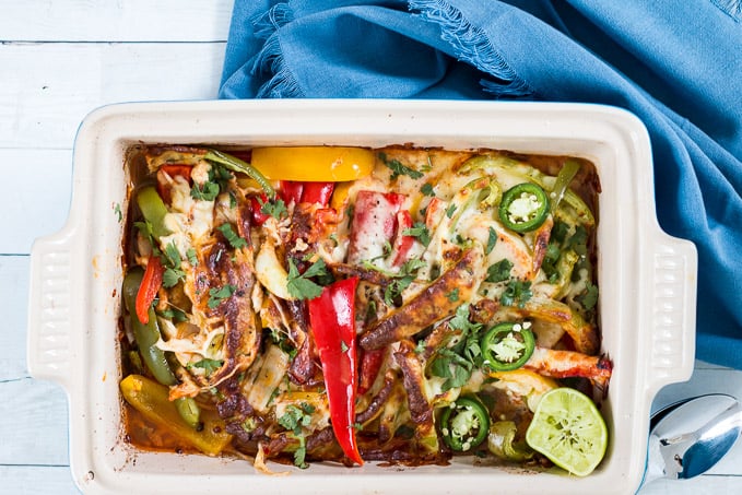 Chicken fajita casserole in a large earthenware dish with a blue cloth surrounding it