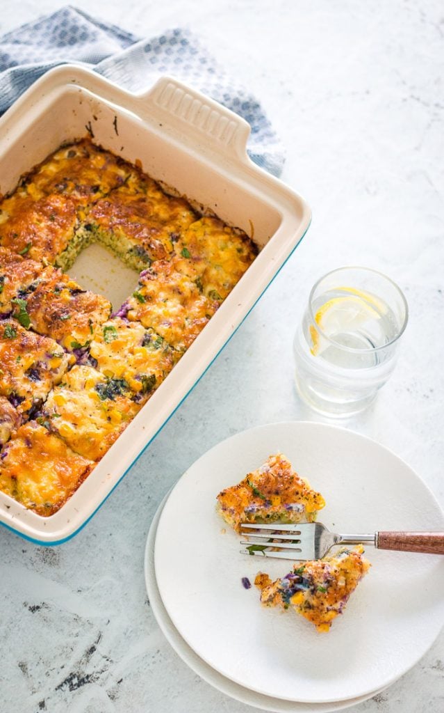 broccoli cheddar rainbow veggie slice in a blue casserole dish with one slice on a white plate