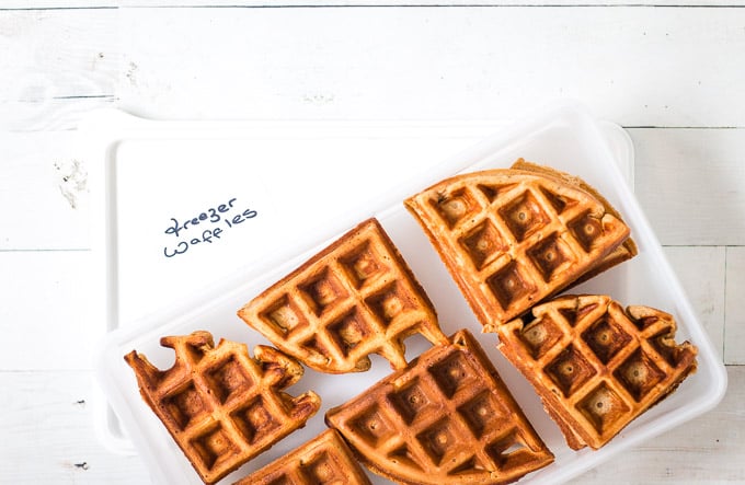 frozen waffles being transferred to a ziplock bag on which 'freezer waffles is written'