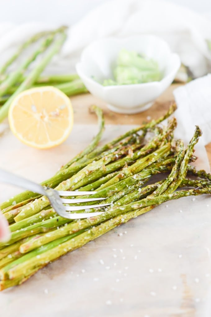 Air fryer asparagus on a wooden board with lemons in the backgroun