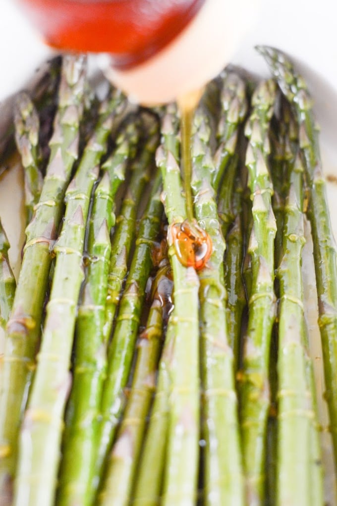 Honey being squeezed on top of asparagus