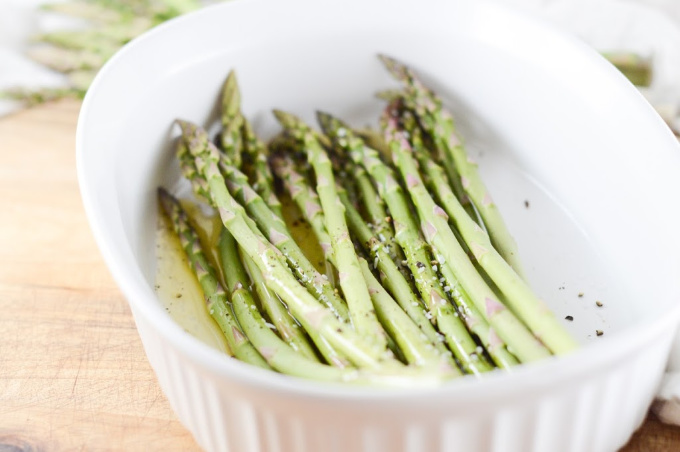 spears of asparagus laid in a white dish