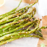 air fryer asparagus lying on parchment paper with sprinkles of sea salt on top