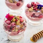 Raspberry chia pudding decorated with edible flowers, buckinis and cacao nibs