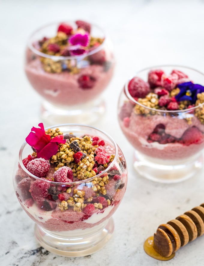 Raspberry chia pudding decorated with edible flowers, buckinis and cacao nibs