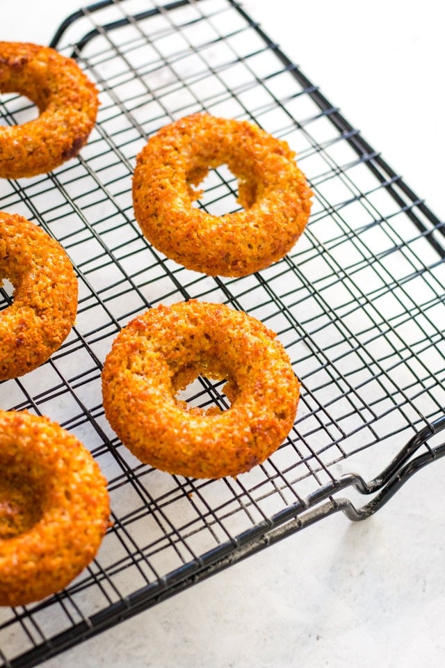 baked banana donuts on a black cooling rack against a white background