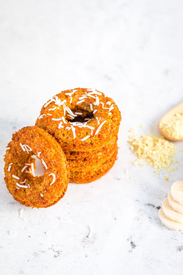 stack of banana donuts topped with coconut flakes on a white background