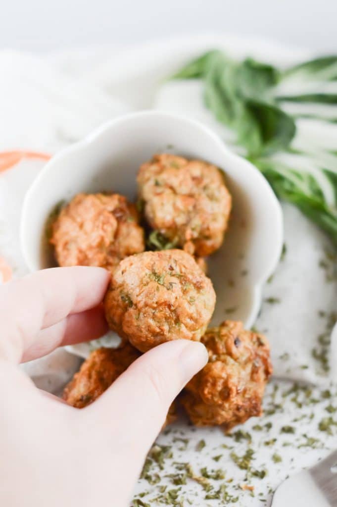 a hand picking up a turkey meatball made in the air fryer