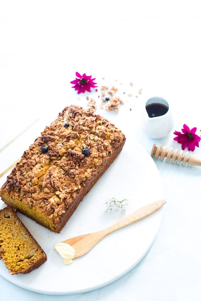 Pumpkin apple bread on a serving platter with a dab of butter and some honey