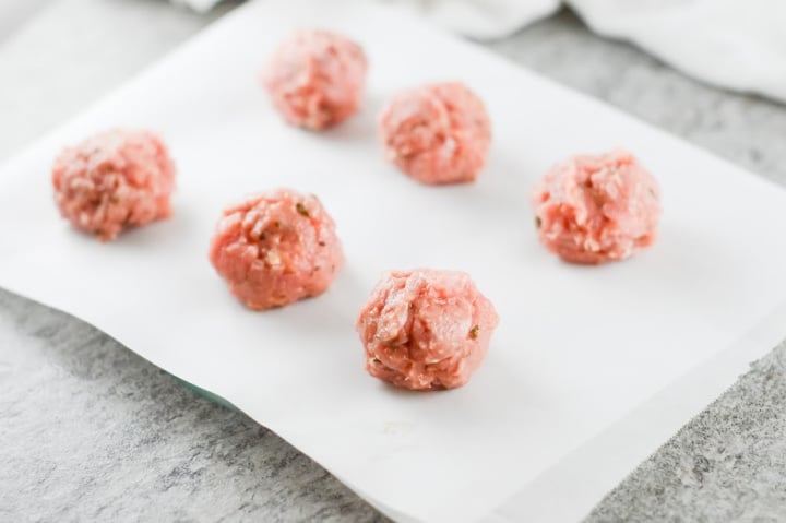 rolled meatballs mixture on some parchment paper