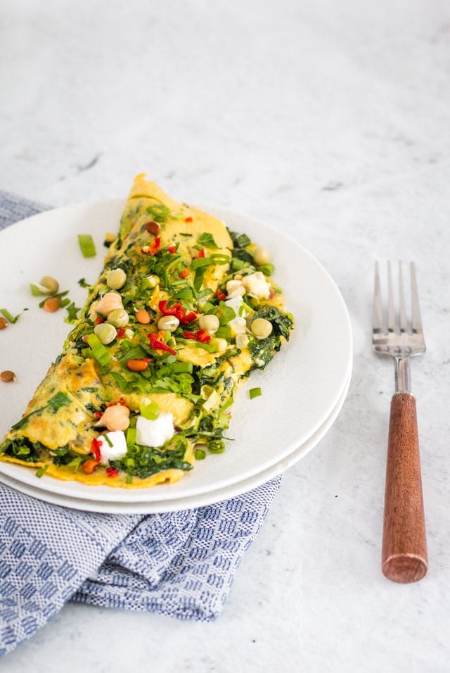 Veggie omelette on a white plate alongside a wooden handled fork