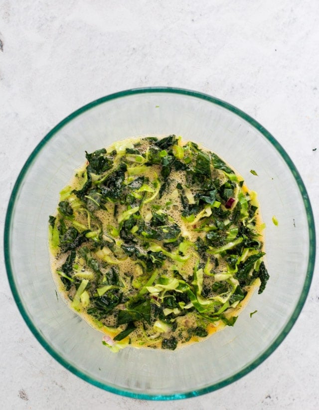 ingredients for spinach omelette being mixed in a glass bowl