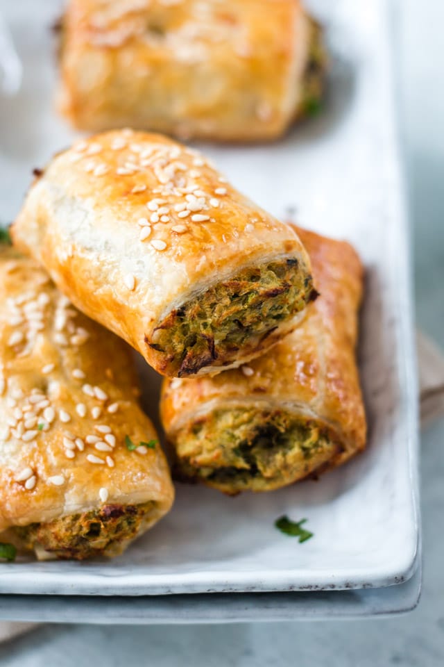 vegan sausage rolls stacked on a white plate