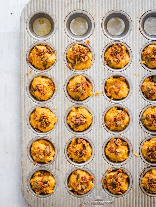 Mini muffin tray with each muffin cup filled ¾ of the way with raw pumpkin muffin batter