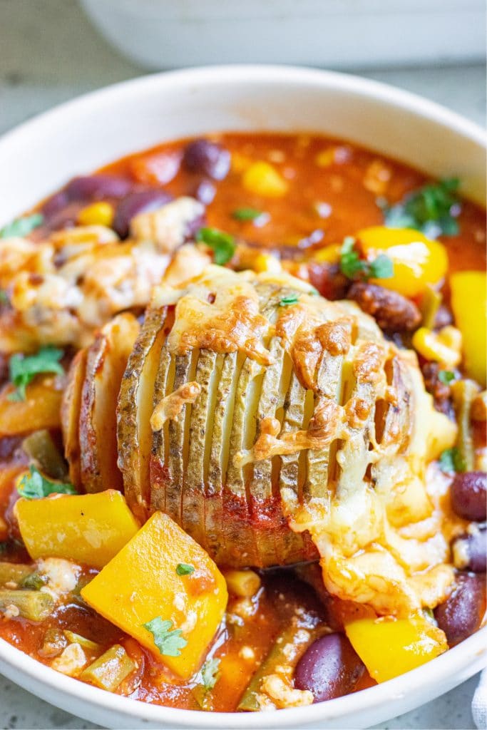 Up close shot of a hasselback potato in a bowl of chili