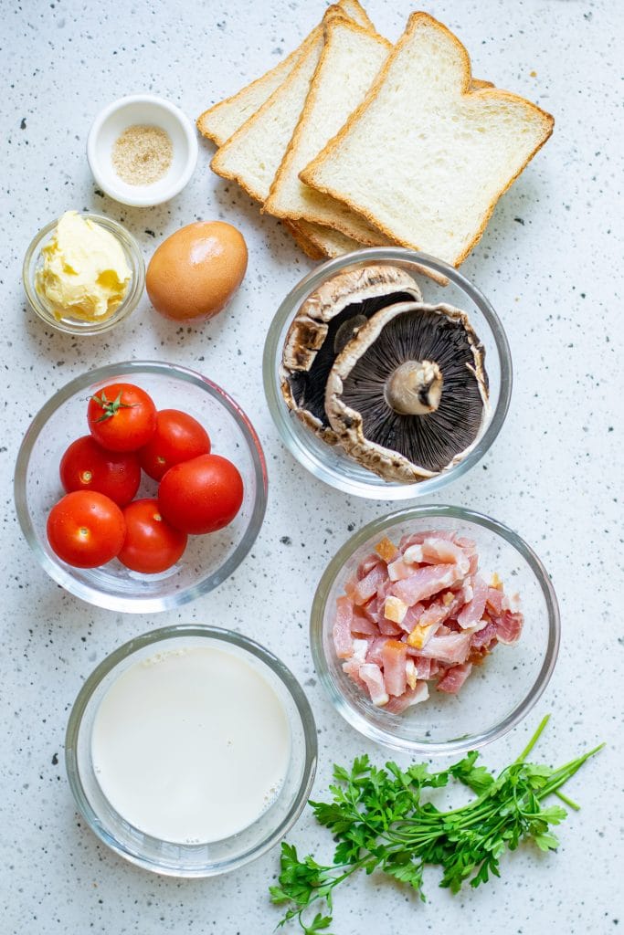 All of the ingredients required for savory french toast displayed in little bowls against an off-white background