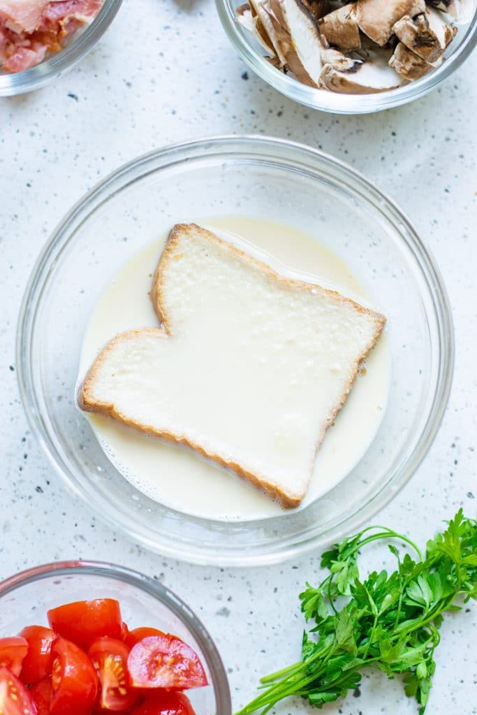 Soaking a slice of bread in an egg and milk mixture for making homemade french toast