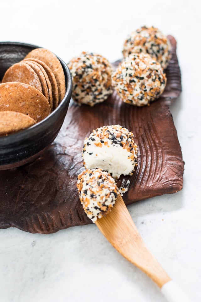 Everything Bagel Cheese Ball being sliced into with a small wooden spoons on a ceramic platter