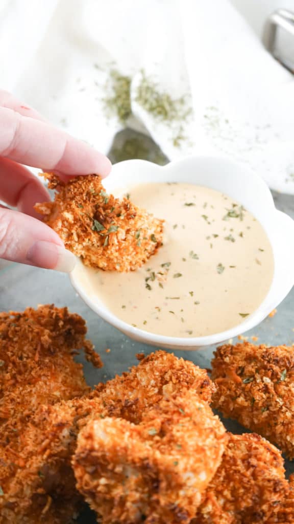 Air Fryer Chicken Nuggets being dipped into a pinkish sauce in a white bowl