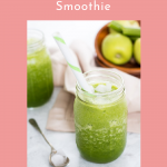 green smoothie with lots of ice served in a mason jar with a bowl of apples in the background