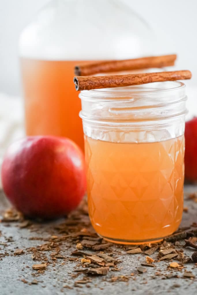 Instant pot apple cider served in a mason jar with a cinnamon stick on top