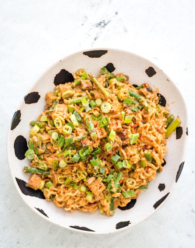 Overhead shot of spicy peanut noodles in a black and white bowl