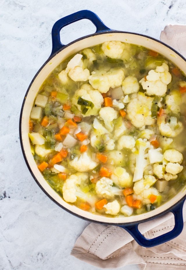 A large dutch oven containing all of the ingredients for cauliflower leek soup prior to being blended