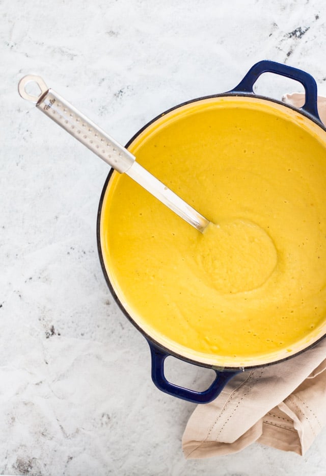 Vegan cauliflower soup in a large pot after being blended, with a ladle inside the dish ready to scoop