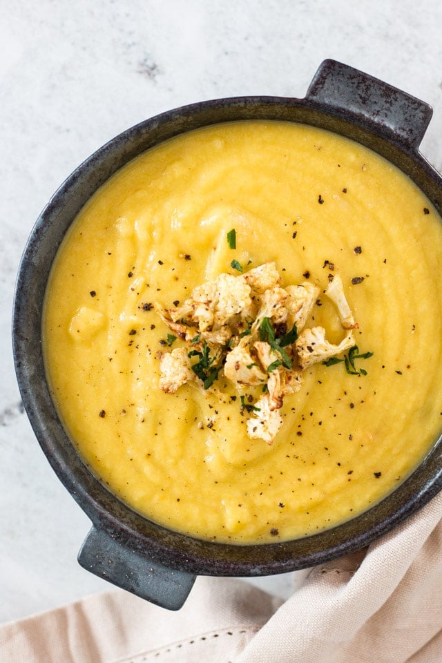 overhead shot of Cauliflower leek soup with roasted cauliflower florets and parsley sprinkled on top