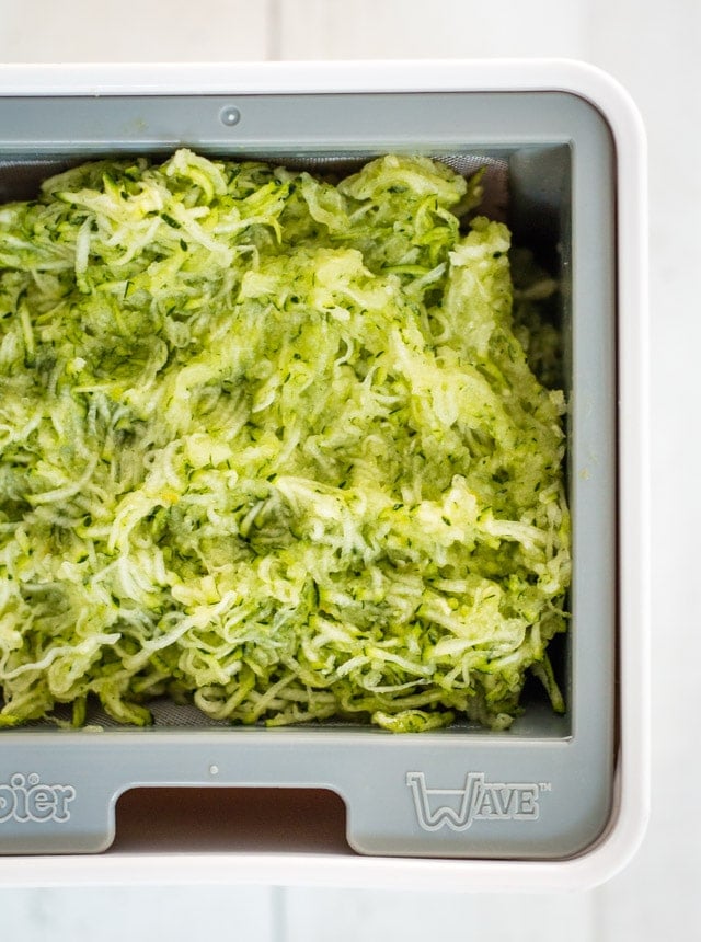 Grated zucchini in the basket of a yogurt strainer