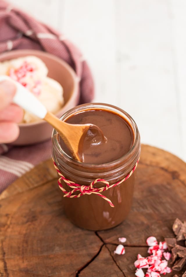 Up close shot of a wooden spoon in a jar of chocolate sauce