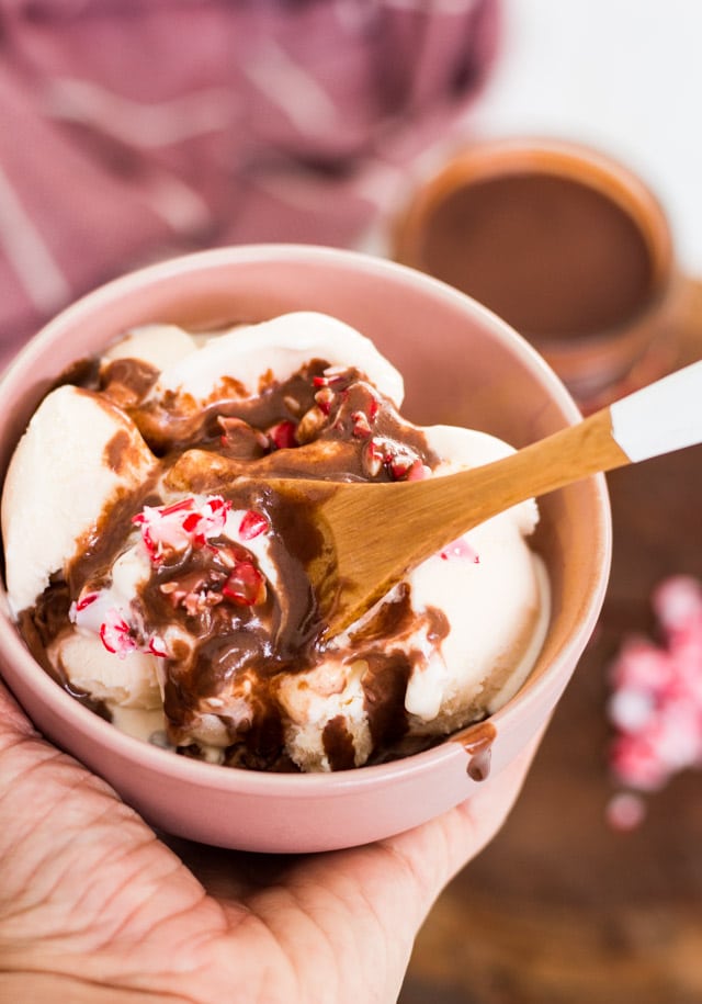 Homemade chocolate sauce drizzled on top of vanilla ice cream in a small pink bowl