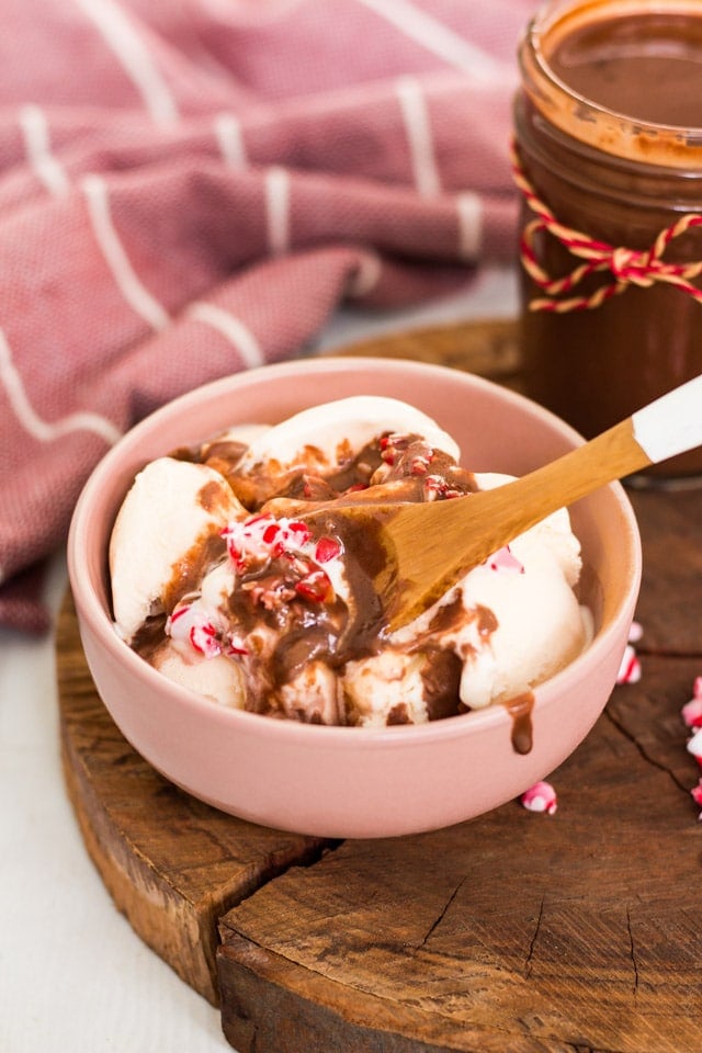 A pink bowl containing vanilla ice cream and a chocolate drizzle poured on top